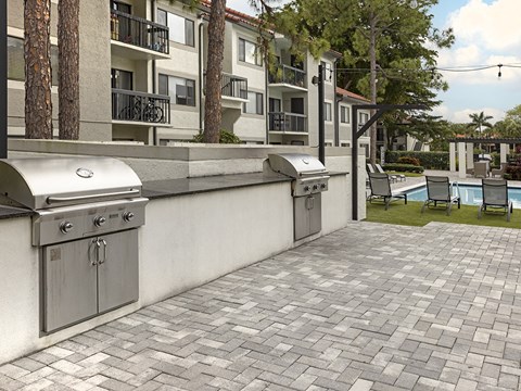 a patio with two stainless steel barbecue grills on it